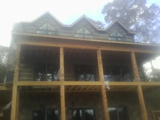 Dormers and porch framing on a large log home under construction — Roof Coating work by our crew in Gorham